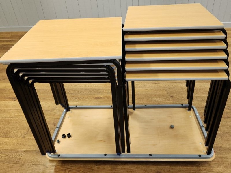 Twelve square fixed leg tables are kept on a trolly in the main storeroom.